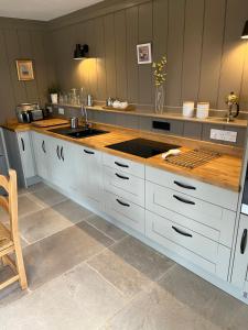 a kitchen with white cabinets and a sink at Luxury Lodge @ Ewen Barn - private 5* retreat in Cirencester