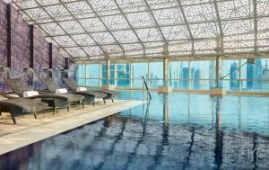 uma piscina com cadeiras num edifício em InterContinental Doha The City, an IHG Hotel em Doha