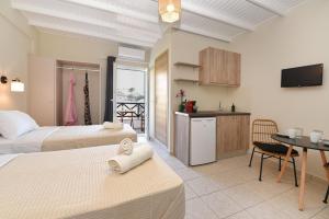 メガス・イアロス・ニテスにあるGlafki Studios Syrosのベッドルーム1室(ベッド2台付)、キッチン(テーブル付)