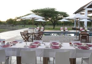 una mesa con platos, servilletas y sillas y una piscina en Emanya@Etosha, en Namutoni