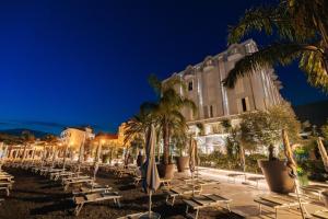 une rangée de chaises longues et de palmiers devant un bâtiment dans l'établissement Hotel Palma, à Tivat