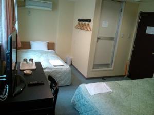 a hotel room with two beds and a desk and a shower at City Inn Nishi Tanabe in Osaka