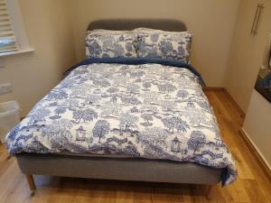 a bed with a blue and white blanket on it at London Luxury Studio Flat 4 min to Ilford Station with FREE parking FREE WiFi in Ilford