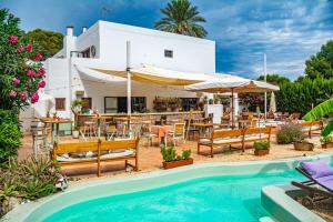 un complejo con piscina, mesas y sillas en Boutique Hostal La Curandera de Salinas, en Ibiza