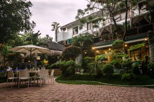 an outdoor patio with tables and chairs and an umbrella at GIARDINO ROMANTICO in Dumaguete