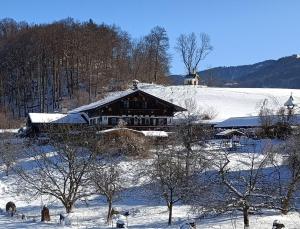 ein großes Gebäude auf einem schneebedeckten Feld mit Bäumen in der Unterkunft Weinfeldhof in Berchtesgaden