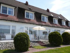 a white house with an umbrella and chairs and bushes at Rezydencja Nad Jeziorem Łebsko in Łeba