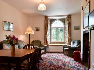ein Wohnzimmer mit einem Tisch, Stühlen und einem Fenster in der Unterkunft Honeybags-uk12422 in Widecombe in the Moor