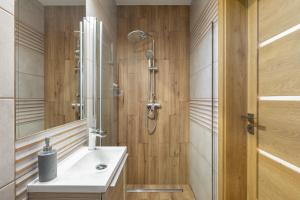 La salle de bains est pourvue d'une douche et d'un lavabo blanc. dans l'établissement DOMKI TU I TERAZ, à Szczawnica