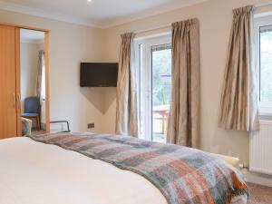 sypialnia z łóżkiem, telewizorem i oknami w obiekcie Lucys At The Grange - Uk11519 w mieście Mockerkin