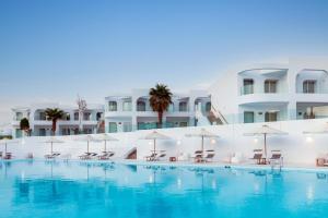 een zwembad met stoelen en parasols voor een gebouw bij Meraki Resort Sharm El Sheikh Adults only in Sharm El Sheikh
