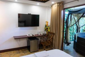 Habitación con escritorio y TV en la pared. en GIARDINO ROMANTICO, en Dumaguete