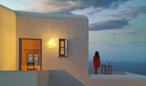 a woman in a red dress standing on a building at Belvedere Apartments in Chora Folegandros