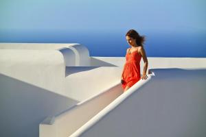 a woman in a red dress is walking on a ledge at Belvedere Apartments in Chora Folegandros