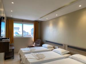 une chambre d'hôtel avec trois lits et une chaise dans l'établissement Hotel Sandis, à Santarém
