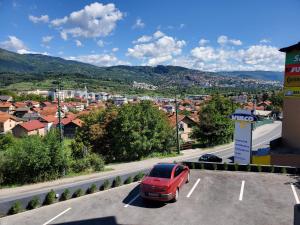 een rode auto staat geparkeerd op een parkeerplaats bij Sleep and drive cosy in Sarajevo