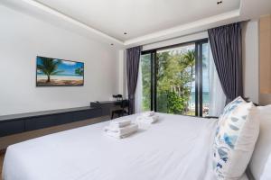 um quarto com uma grande cama branca e uma grande janela em By The Beach Home in Patong em Praia de Patong