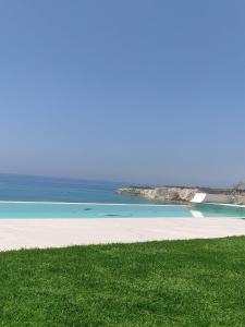 a beach with green grass and the ocean at Villa Gentile in Eraclea Minoa