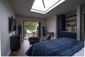 a bedroom with a blue bed and a skylight at Honeysuckle Lodge in Knaresborough