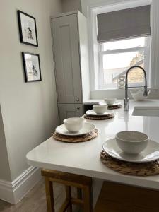 a kitchen counter with bowls and plates on it at Kings Apartment, 83 Kings Road in Harrogate
