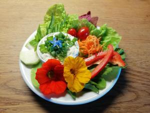 einen Teller Salat mit Blumen und Gemüse auf dem Tisch in der Unterkunft Penzion Nadějov in Kašperské Hory