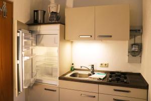 eine kleine Küche mit einer Spüle und einem offenen Kühlschrank in der Unterkunft Ferienhaus in Kühlungsborn in Kühlungsborn