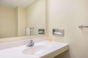 a white bathroom with a sink and a mirror at Haven Inn & Suites St Louis Hazelwood - Airport North in Hazelwood