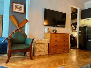ein Wohnzimmer mit einem TV, einem Stuhl und einer Kommode in der Unterkunft Old Town Krakow! Amazing location & character in Krakau
