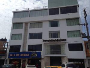 a tall white building with cars parked in front of it at Hotel Ivansino Inn in Chimbote