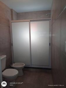 a bathroom with a toilet and a glass shower stall at Lugar Encantador con estacionamiento gratuito. in Olavarría