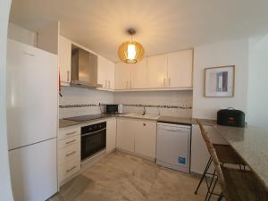 Una cocina con gabinetes blancos y un refrigerador blanco. en Jardines Del Puerto, en Denia