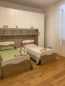 1 dormitorio con 2 camas y armarios blancos en La Lanterna sul mare en Livorno