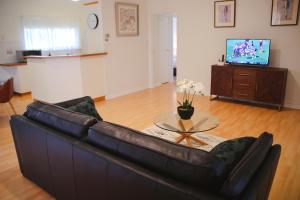 a living room with a leather couch and a table at Wagga Showground Villas in Wagga Wagga