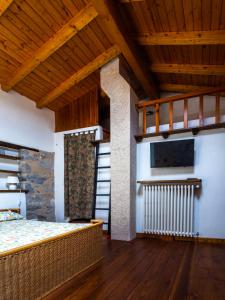 a bedroom with a bed and a television and wooden ceilings at Deliziosa Casetta Sull'Appennino Toscano in Montefegatesi