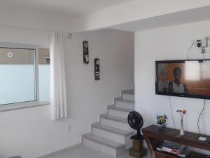 a living room with a staircase with a tv on the wall at Praia do Sonho in Palhoça
