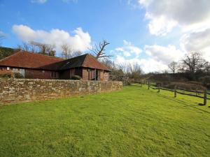 a house in a field next to a stone wall at The Barn At Banks Cottage in Pulborough