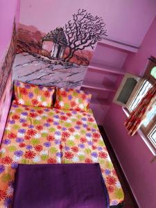 a bedroom with a bed with a painting on the wall at TEMPLE VIEW GUEST HOUSE in Hampi