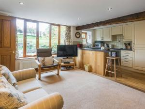 a living room with a couch and a kitchen at Castle House Cottage in Kirkby Stephen