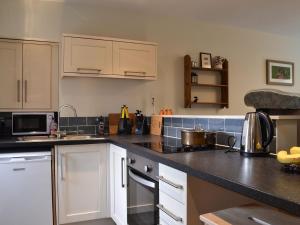 een keuken met witte kasten en een zwart aanrecht bij Coopers Cottage in Haverthwaite