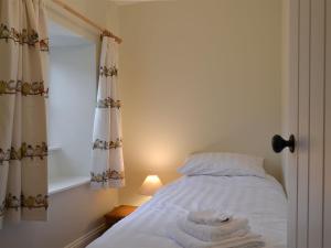 een slaapkamer met een bed met witte lakens en een raam bij Coopers Cottage in Haverthwaite