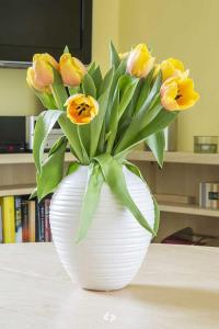オストゼーバート・ディアーハーゲンにあるSTRANDPERLE App Nr 01 max 4 Persのテーブルの上に黄色い花が咲き誇る白い花瓶