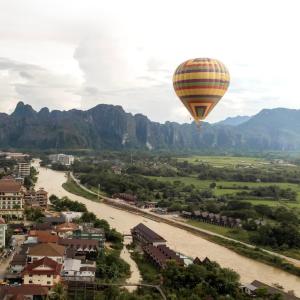 a hot air balloon flying over a river at Vangvieng Rock Backpacker Rooftop Hostel in Vang Vieng