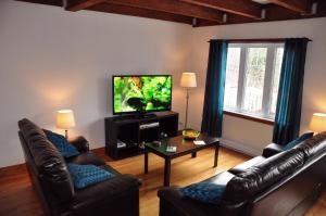 a living room with two leather couches and a flat screen tv at Chalet Rouge in New Richmond