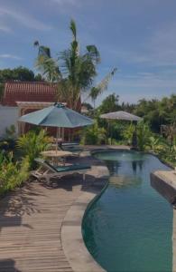 una piscina con sombrillas y una terraza de madera en The Green ujung Villa en Ujung