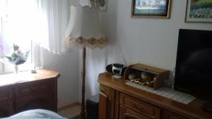 Zimmer mit einer Lampe und einer Kommode mit einem TV in der Unterkunft Doms-Baumhammer, Auf dem Baer 4 in Viersen