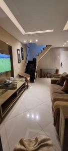 a living room with a couch and a tv and stairs at Cobertura Duplex Vista Mar in Mangaratiba