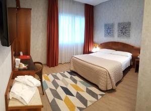 ein Hotelzimmer mit einem großen Bett und einem Tisch in der Unterkunft Hotel Poppi in Mira