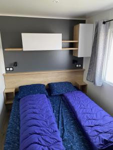 ein Schlafzimmer mit einem Bett mit lila Kissen darauf in der Unterkunft Oostkapelle Chalet JD 56 In de Bongerd in Oostkapelle
