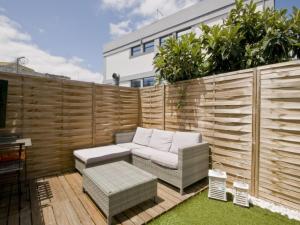 a backyard with a wooden fence with a couch and chairs at Casa em Lisboa in Lisbon