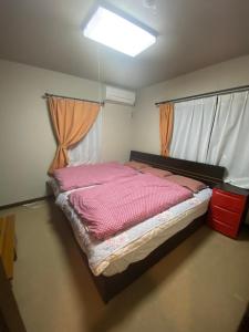 1 dormitorio con 1 cama grande con sábanas rosas en 澄心小筑.房东在住型民宿.雄琴车站免费接送, en Otsu